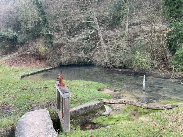 L'Orbiquet jaillit au pied du coteau après avoir emprunté une succession de siphons. L'eau est à une température stable de 10º, celle du sous-sol. A proximité de la source se trouve des lavoirs et un moulin. nous allons continuer par le chemin que l'on devine au-dessus de la source.