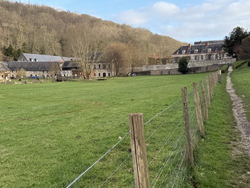 Le chemin va déboucher en face de l'abbaye Saint-Wandrille dont on devine déjà les bâtiments, avec à gauche&nbsp;la ferme « D'en Bas ».