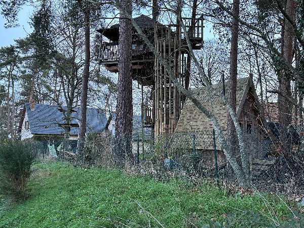 A droite du chemin, une impressionnante cabane, et un parcours d'accrobranche dans un jardin.