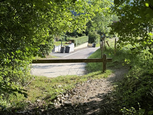 Nous sortons du bois. On peut voir en face un solide poteau métallique présentant une flèche sur fond en damier. On voit encore quelques poteaux identiques dans Rouen. C'est le vestige de balises d'un réseau de balades dans Rouen et sa couronne.